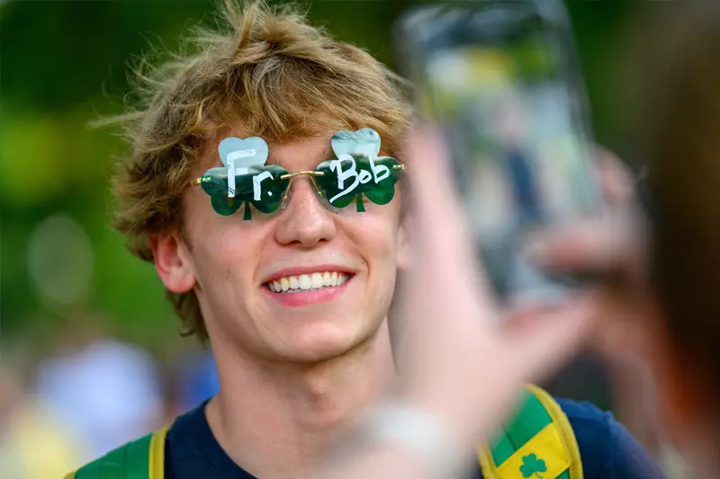 A male student wears shamrock shaped sunglasses with the words Fr and Bob on them.