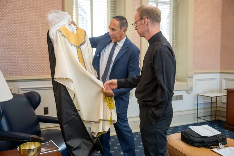 Fr. Bob being presented with cream vestments accented with gold and blue decorations.