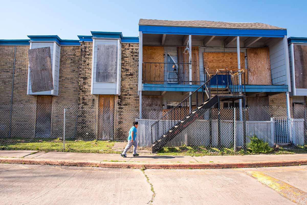 A child walks past boarded-up vacant units in the Rockport Apartments complex, which sustained damage from Hurricane Harvey.