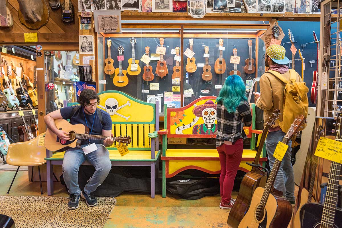 Student journalist Carlos De Loera plays a guitar at Rockin' Robin Guitars & Music store in Houston, Texas.
