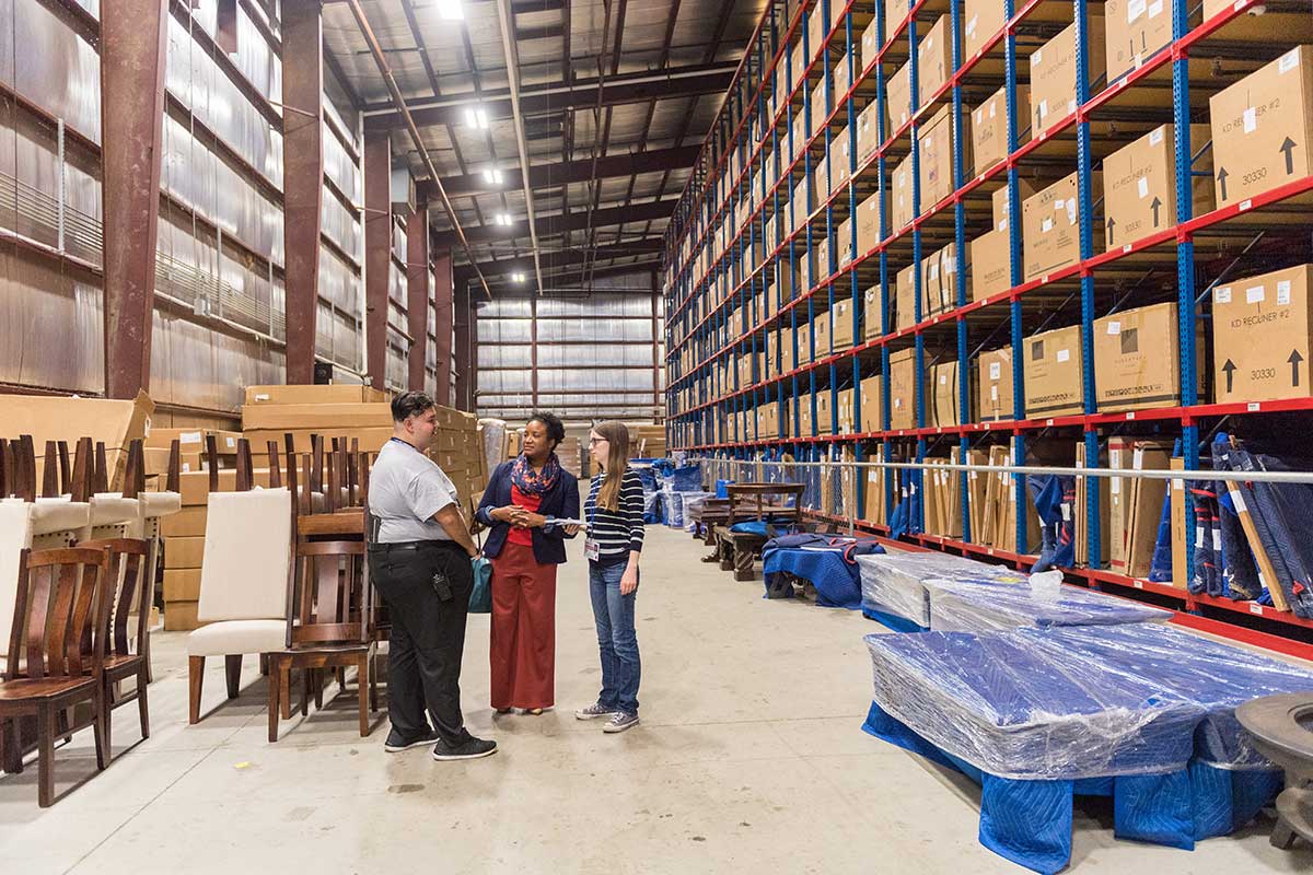 Courtney Becker (right) and Prof. Victoria St. Martin interview employee Ariel Rodriguez in the warehouse at Gallery Furniture.