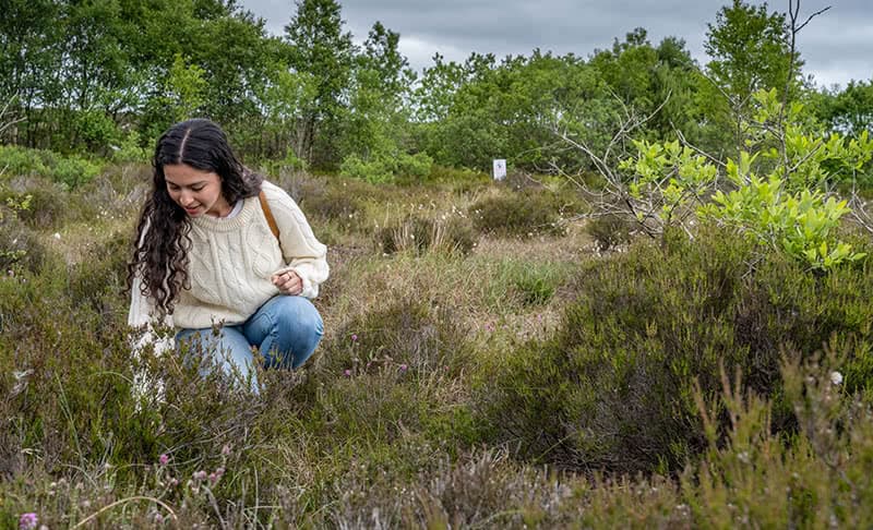 Mariana Silva bending down and observing vegetation.