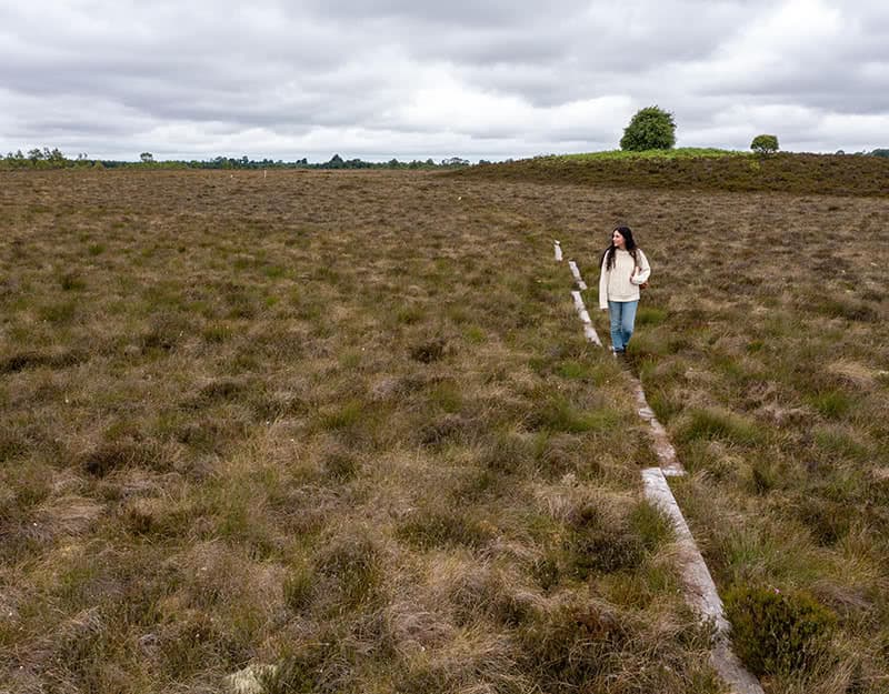 Mariana Silva walking on wooden planks placed through the bogland.