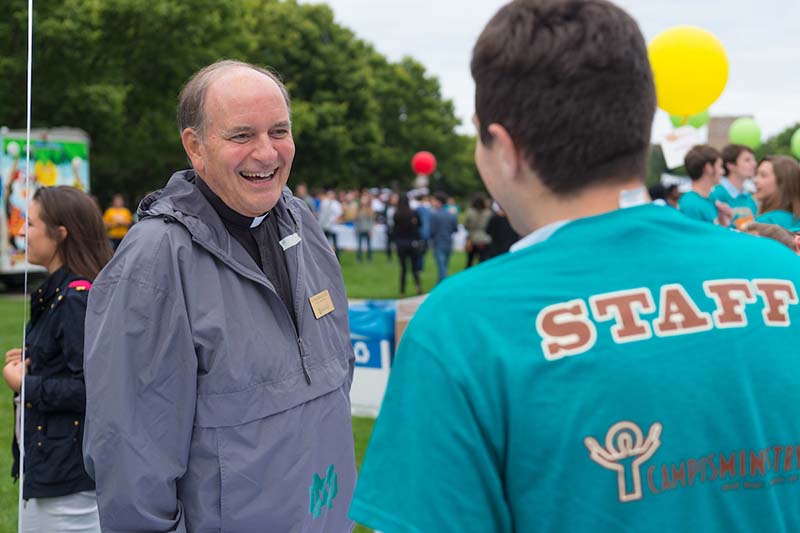 Father Rocca smiles at a student outside on the quad.