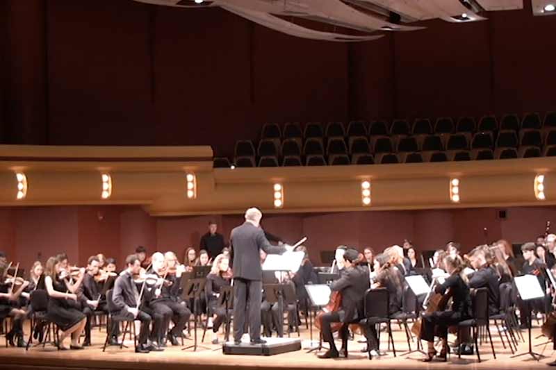 Notre Dame Symphony Orchestra on a stage performing.