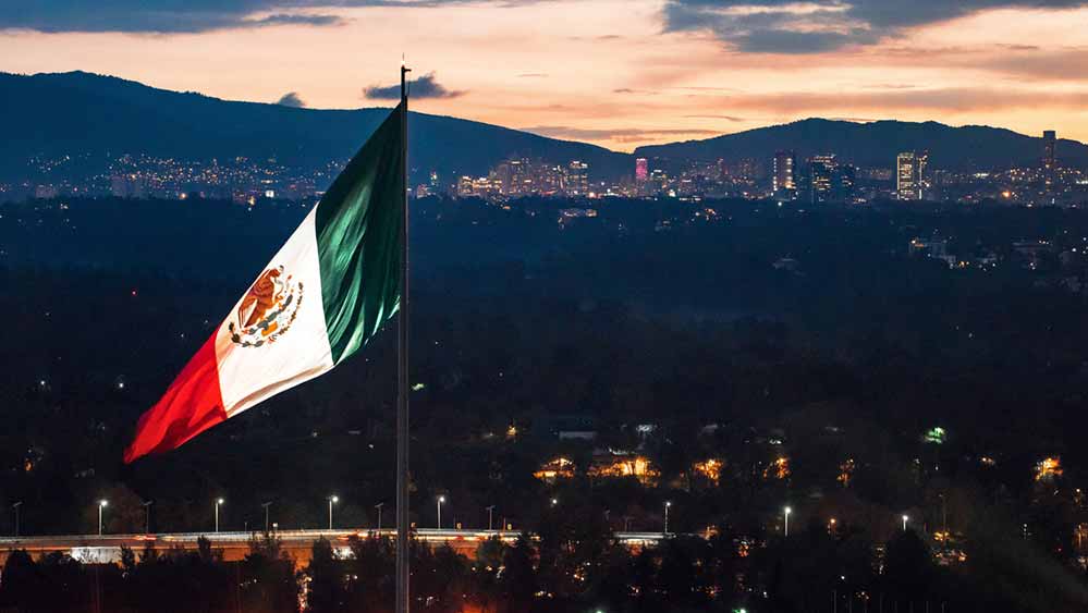 Mexican flag with city in the background