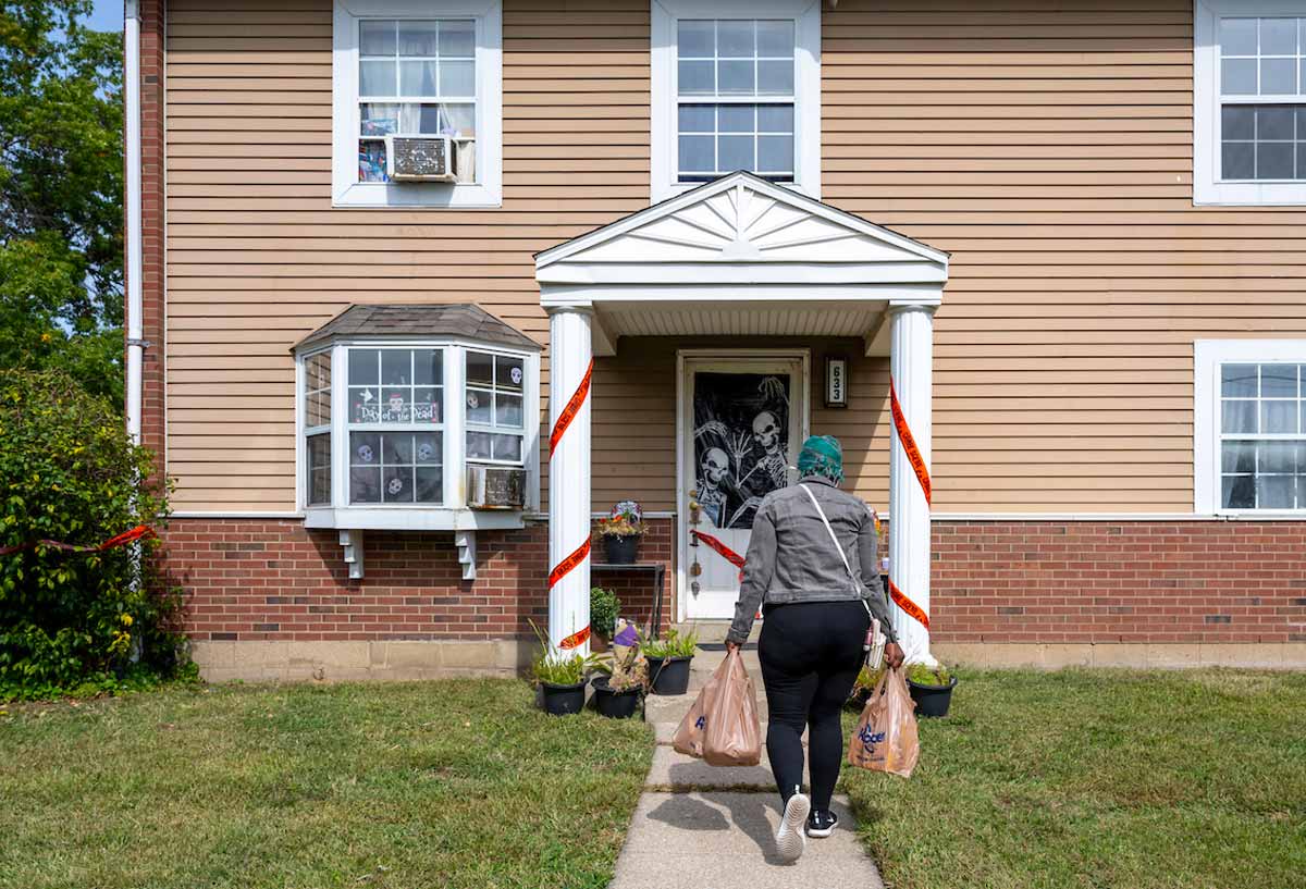 A woman arrives at home with her groceries. Her home is decorated for Halloween.