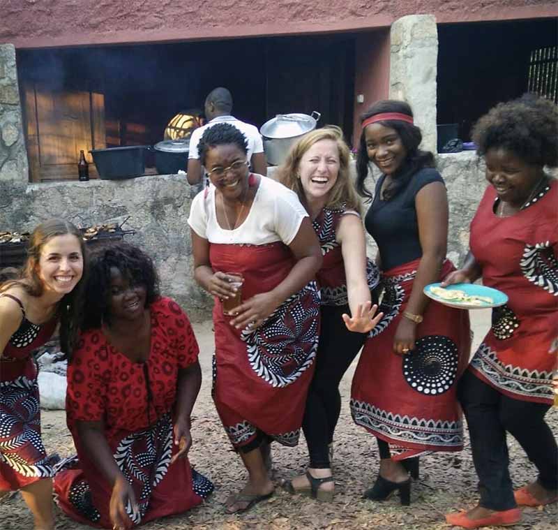 A group of six women posing, dancing, and laughing wearing clothes with the same color and pattern.