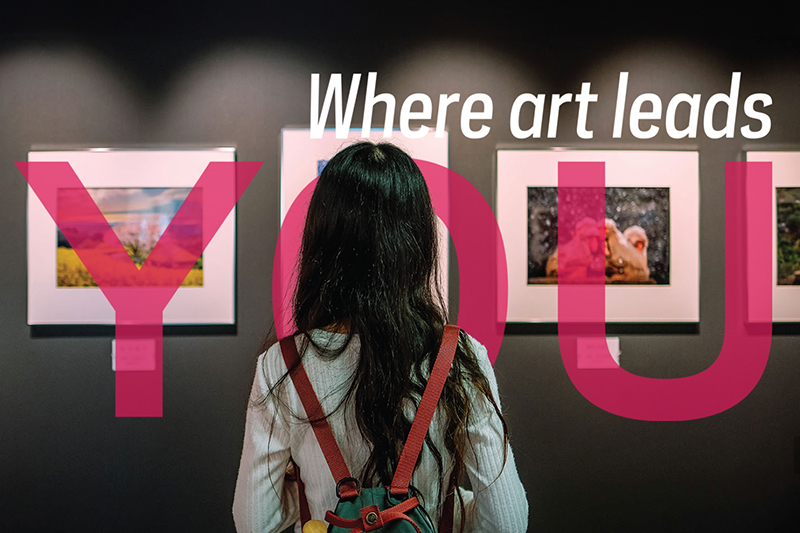 A person facing a wall of photos on exibit at the Snite Museum of Art