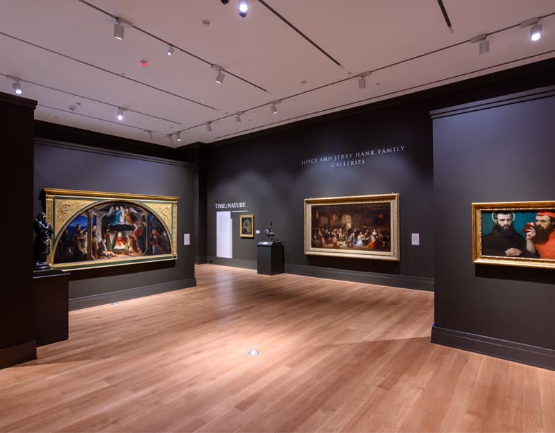 A gallery space with hardwood floors and dark gray walls.