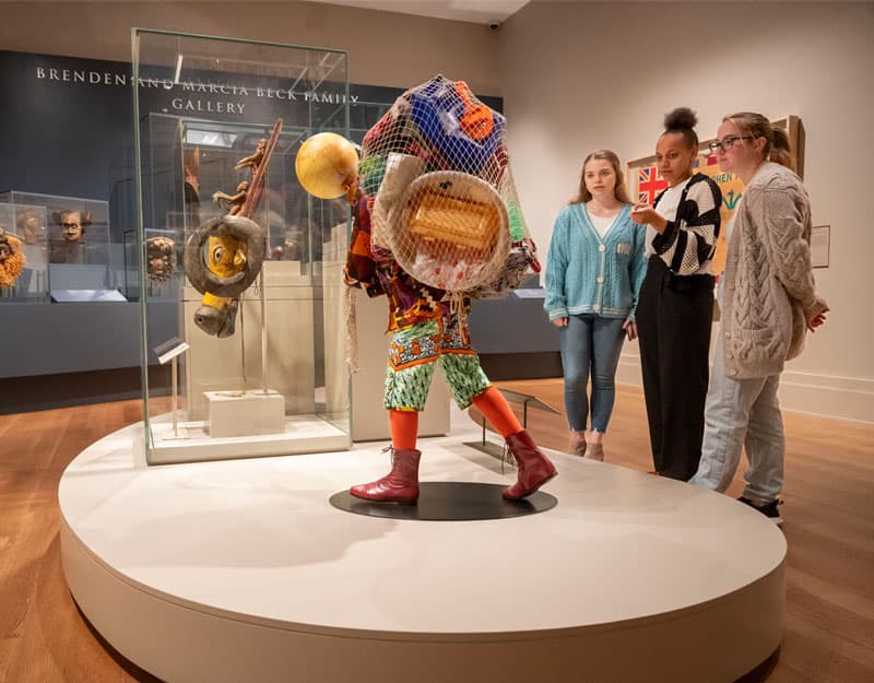 Three students standing by the sculpture Earth Boy by British Nigerian artist Yinka Shonibare.