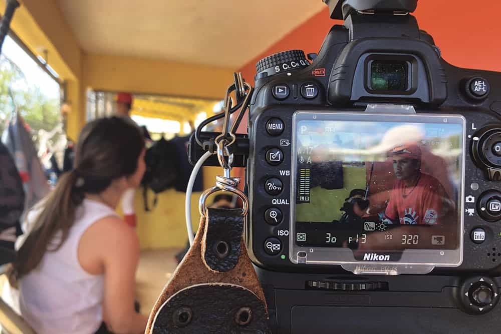 A camera screen focused and in the foreground displays an image of a baseball player.