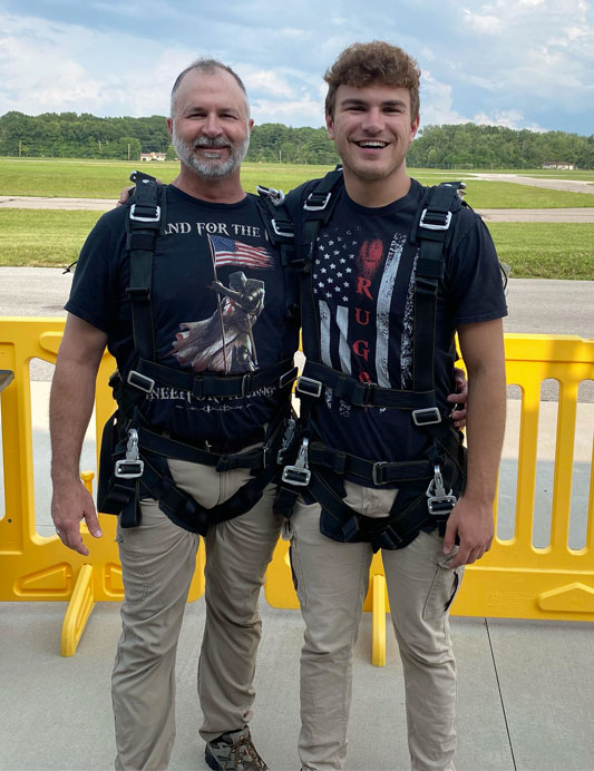 Andrew and his dad wearing harnesses in preparation for skydiving.
