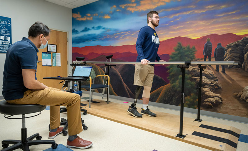 Andrew tries out his new prosthetic leg while the physical therapist observes.