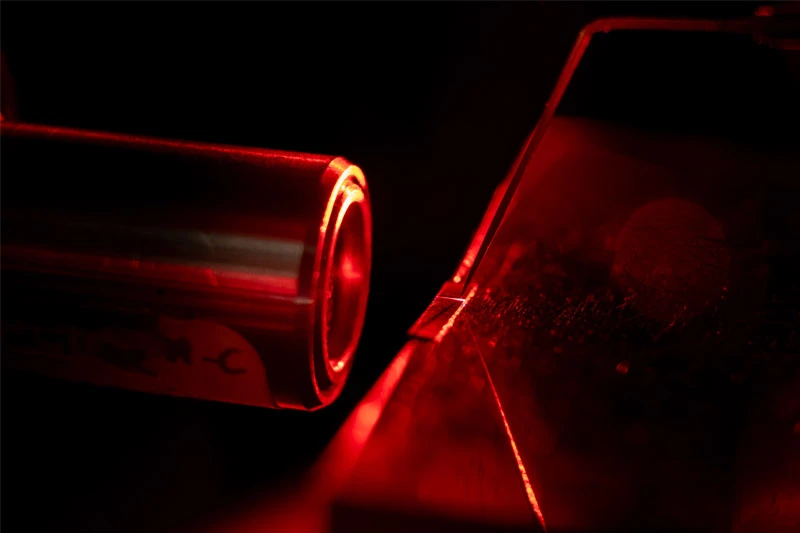 A red laser shines on a dark surface.