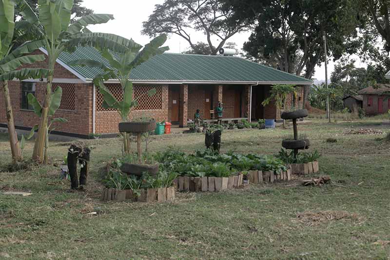 A brick building in the background and a small garden area, parts made using used tires, in the foreground.