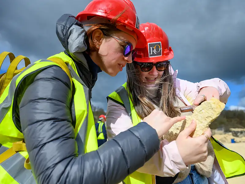 Fitted with hardhats, two Notre Dame architecture students examine stone while visiting a quarry.