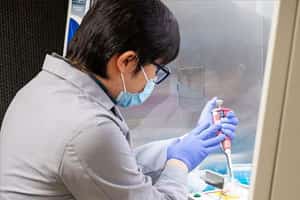 A man in a labcoat works on a COVID-19 test device.