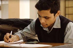 A student studies a piece of paper at a desk.