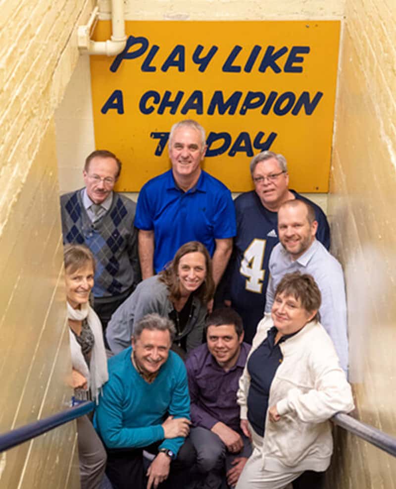 A group of people pose next to the Play Like a Champion sign.