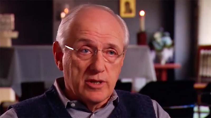 A screenshot from a video of an older gentleman wearing glasses during his interview.