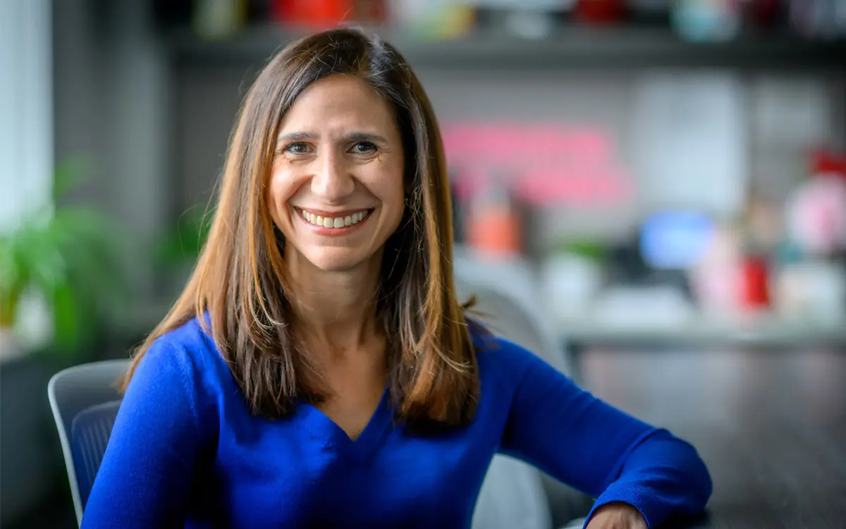 A portrait of Kristin Valentino wearing a blue v-neck sweater.