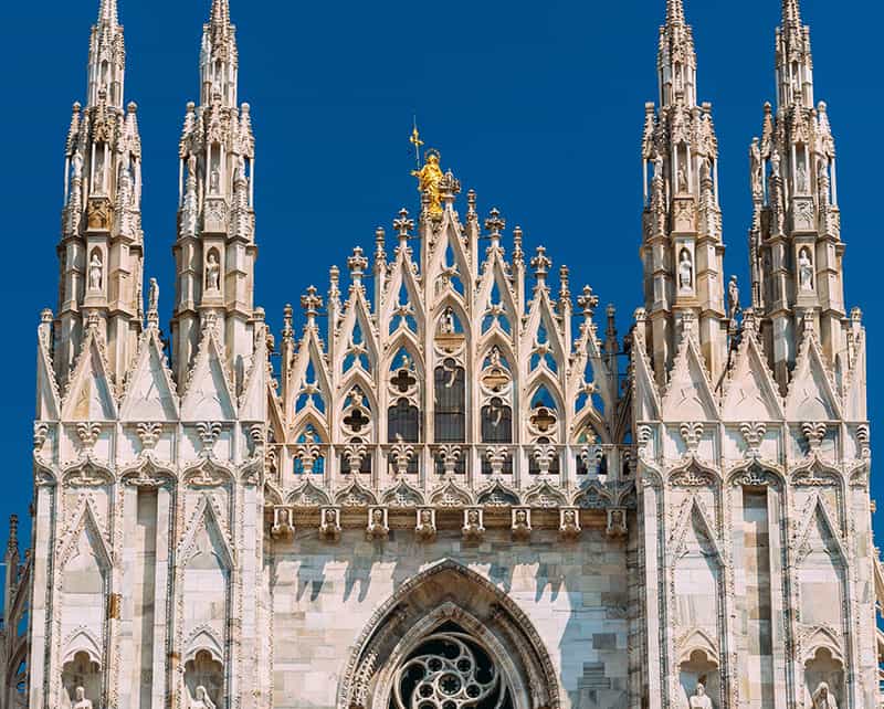 A golden statue of virgin mary atop a cathedral.