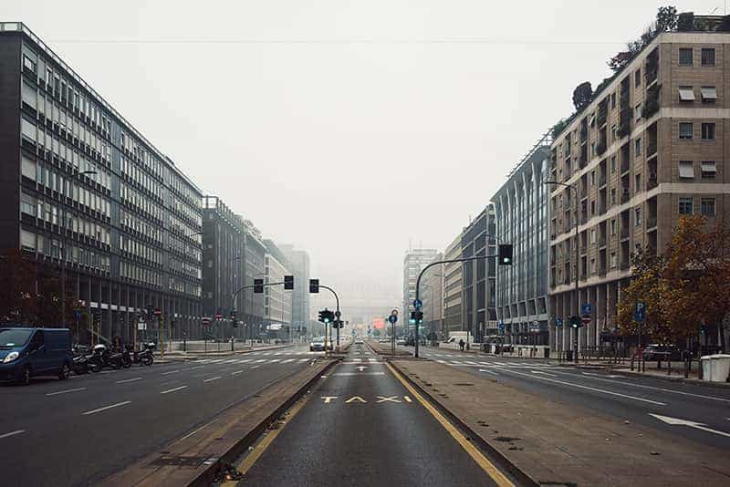 An empty and foggy street view of Milan Central Train Station.