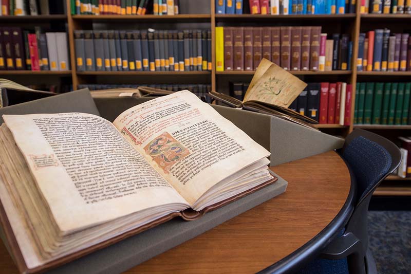Medieval manuscripts sit open on a table in the library. 