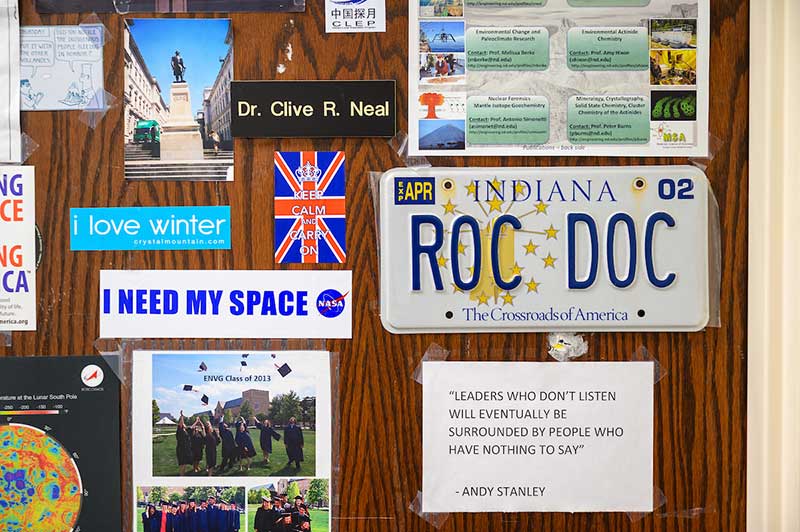 An office door filled with stickers about space, photos, and a license plate that says ROC DOC.
