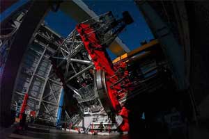 A giant telescope, with red and orange coloring, against a night sky.