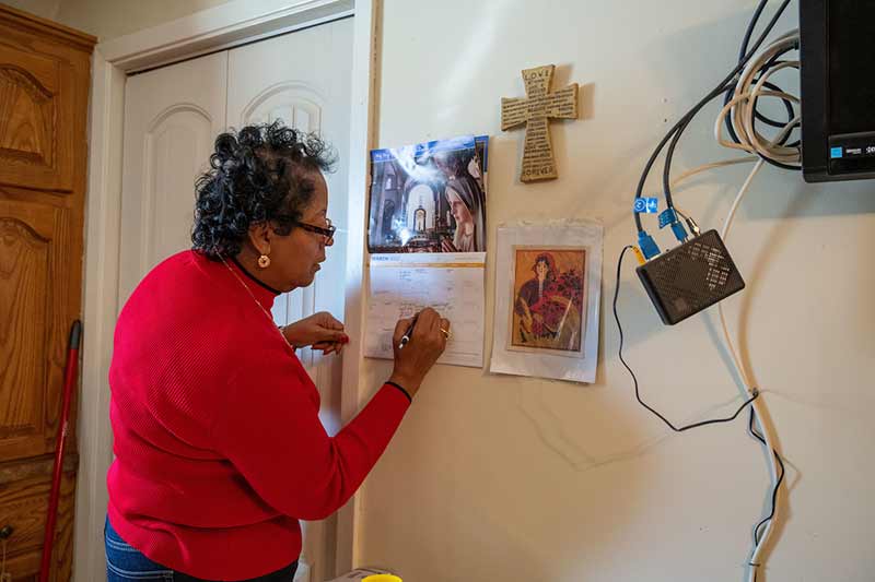 A woman writes something down on a wall calendar.