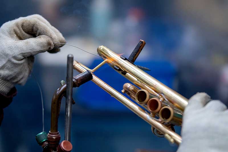 A close up of a trumpet getting soldered.