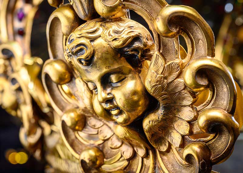 Detail of a gold angel face on a crown.