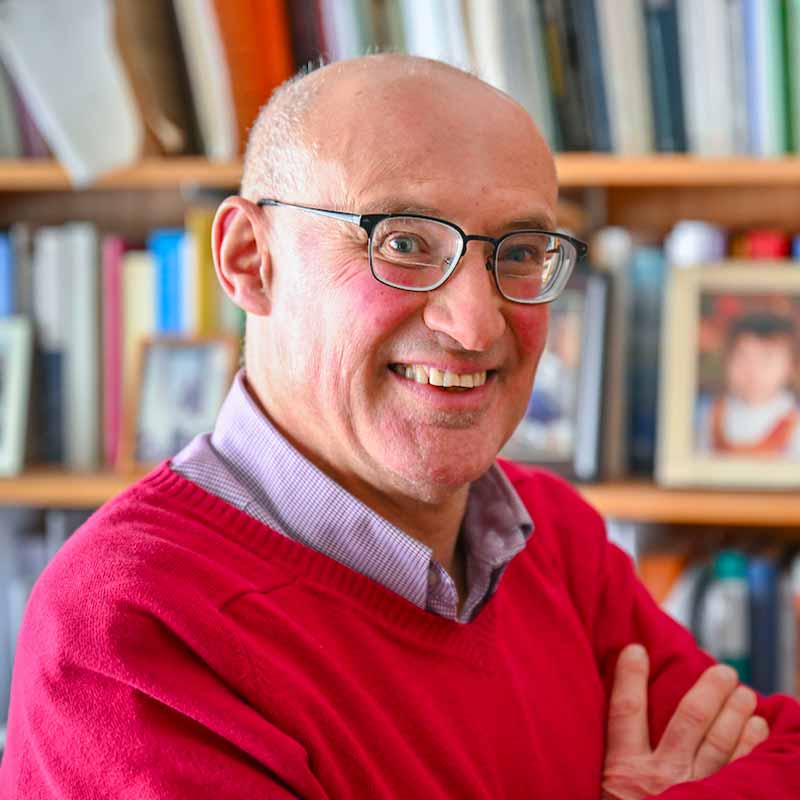 A headshot of Vittorio Hösle in his office, book shelves behind him.