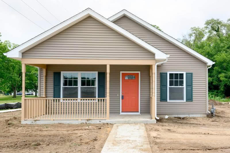 A newly constructed craftsman style house with newly planted grass that has not sprouted yet.