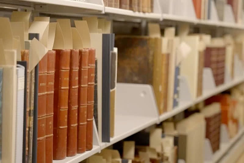 Photo of older books on a bookshelf in a library