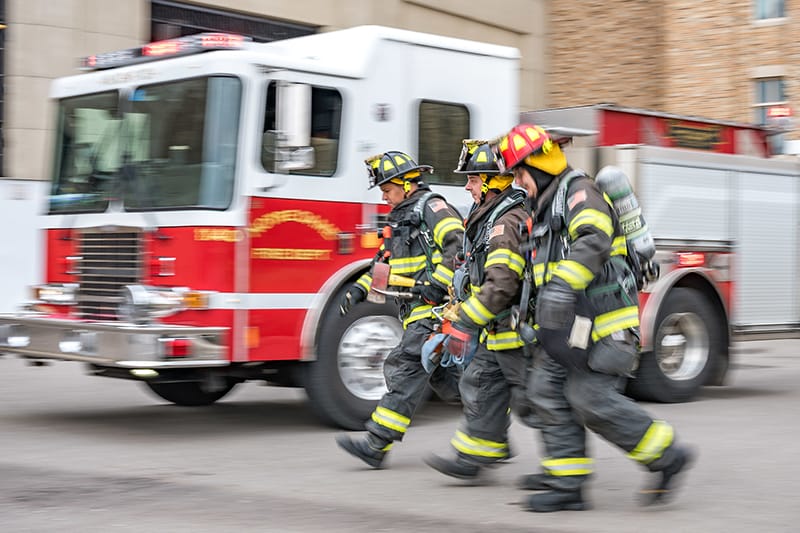 Firefighters in gear walk by a Notre Dame Fire Department truck.