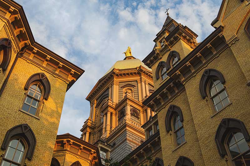 Notre Dame's Main Building and Golden Dome against a cloudy, blue sky.