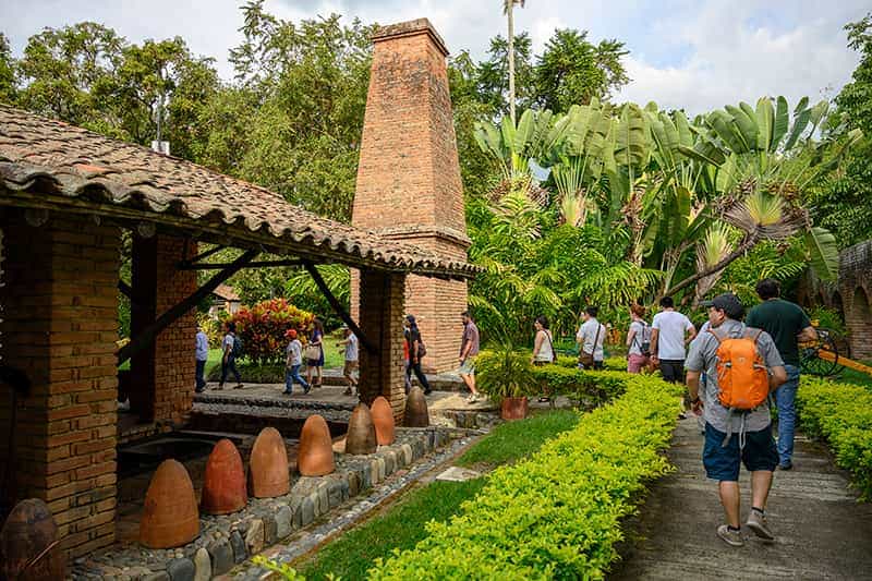 A group of people walk down a path on a tour of the sugar cane museum.