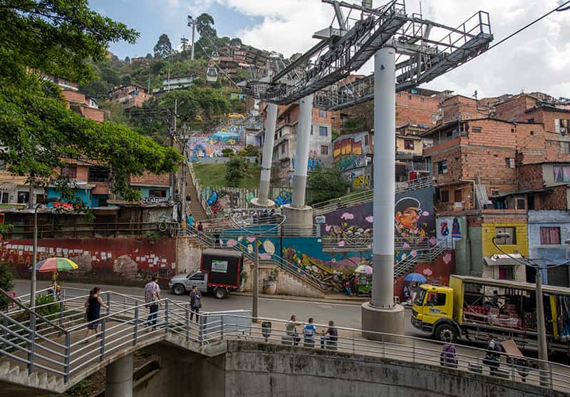 A wide shot of a an urban area filled with street art and cable car lines.