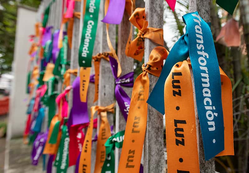 Colorful ribbons tied to a fence that say “Transformation”