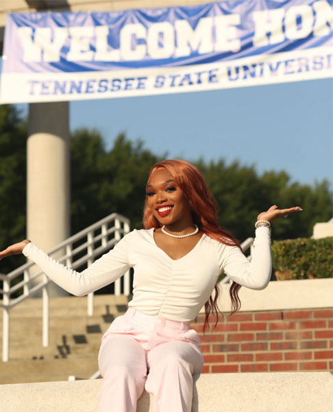 Ahsaunta Fielder stands with arms out in front of a TSU welcome sign.