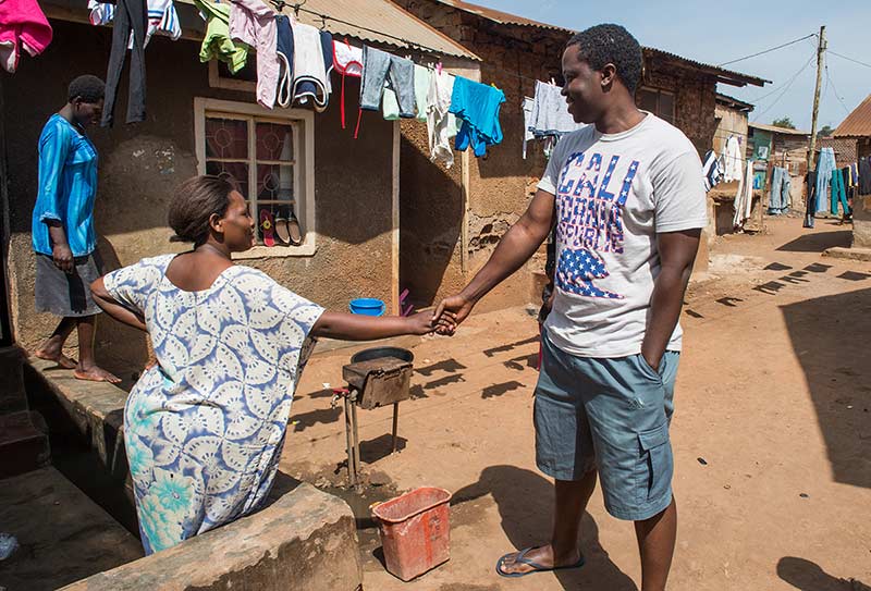 YALI fellow Alex Kawooya, says hello to woman who recognized him during his return visit to Kalerowa slum.