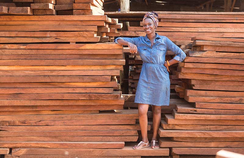 Evelyn Zalwango leans on a stack of wood.
