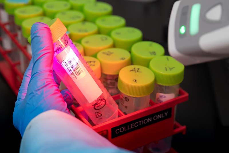 A scanner scans barcode labels on the sample vials.
