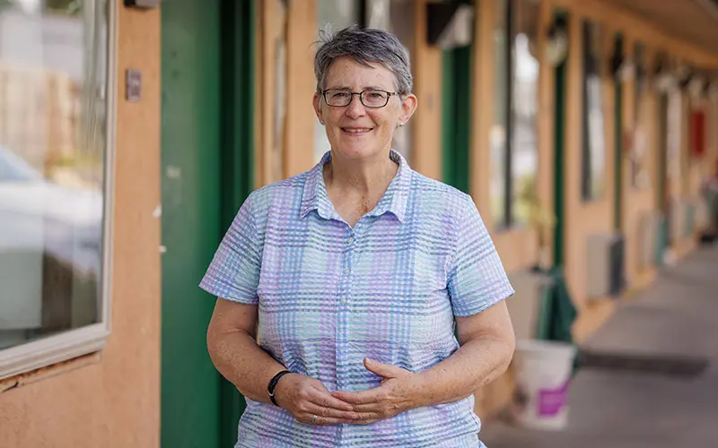 A portrait of Margie Pfiel standing in front of a motel.