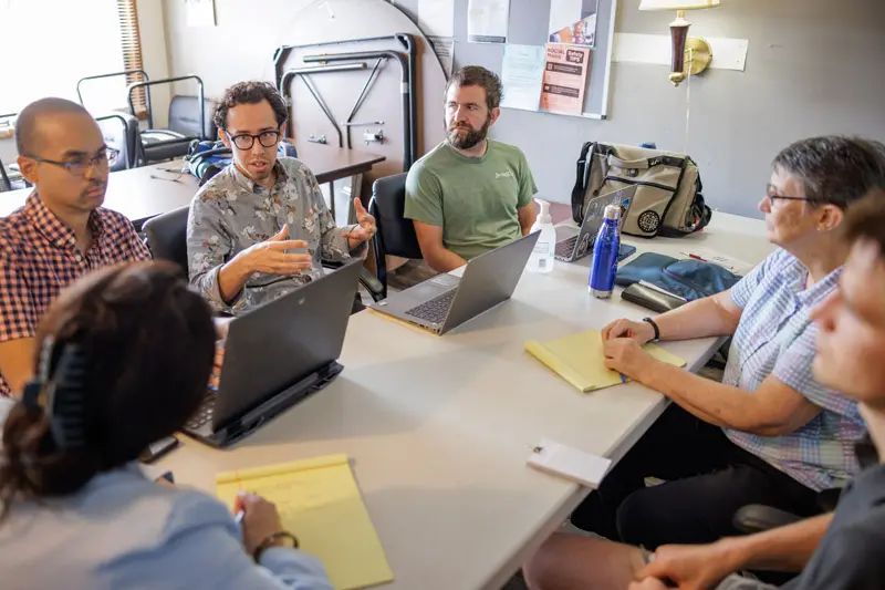 Margie Pfeil sits at a conference table with four men and one woman.