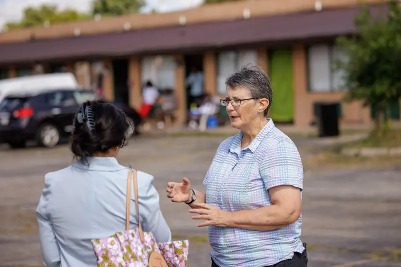 Margie Pfeil stands in front a motel talking to a woman.