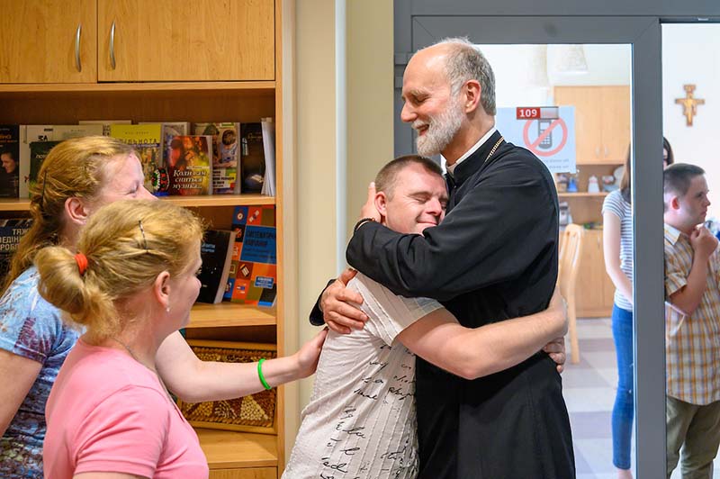 Borys Gudziak wearing vestments hugs a student.